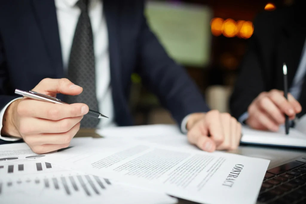 Ejecutivos firmando contrato con gráficos financieros