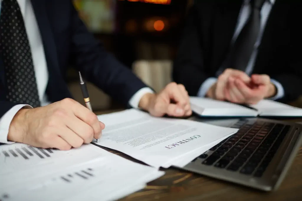 Ejecutivos firmando contrato junto a laptop