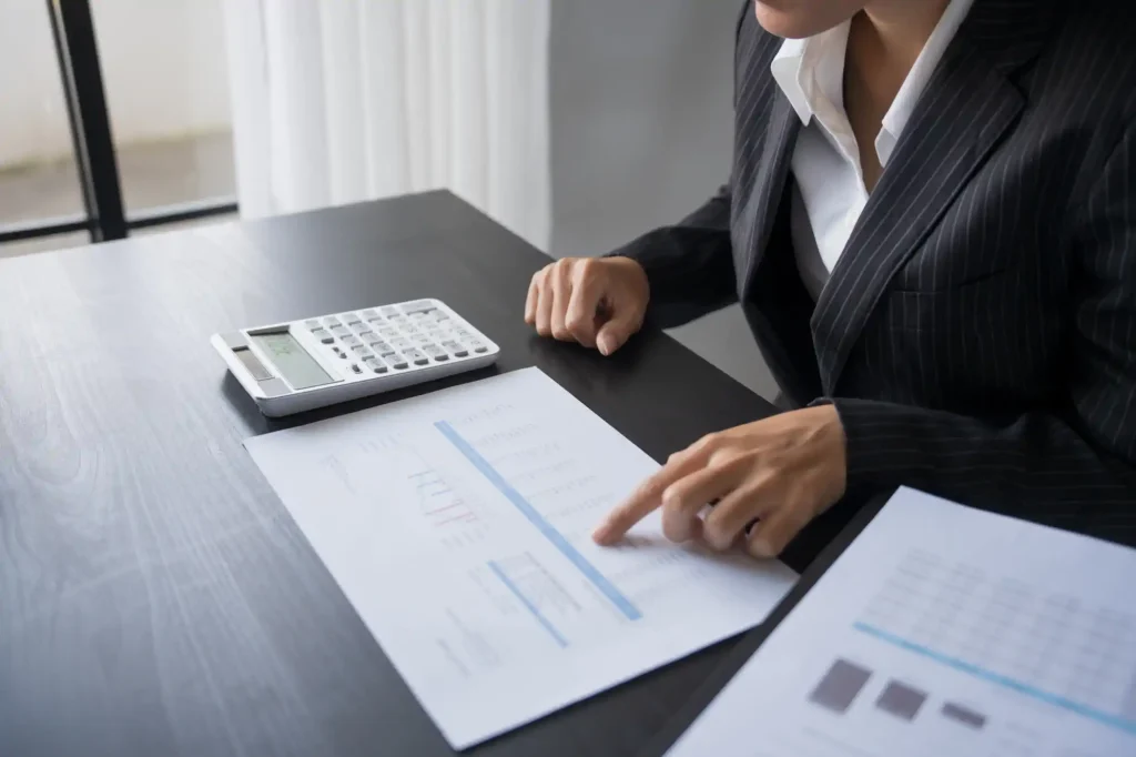 Mujer revisando reportes financieros con calculadora