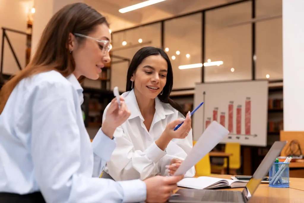 Dos mujeres revisando documentos en oficina moderna