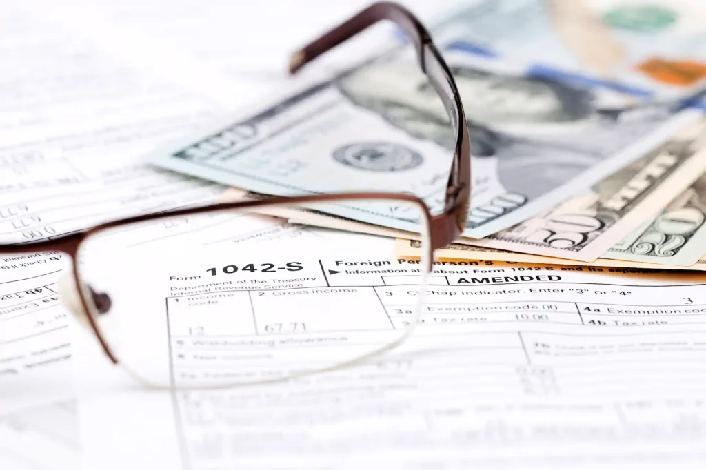 Lentes sobre formulario fiscal 1042-S y dólares