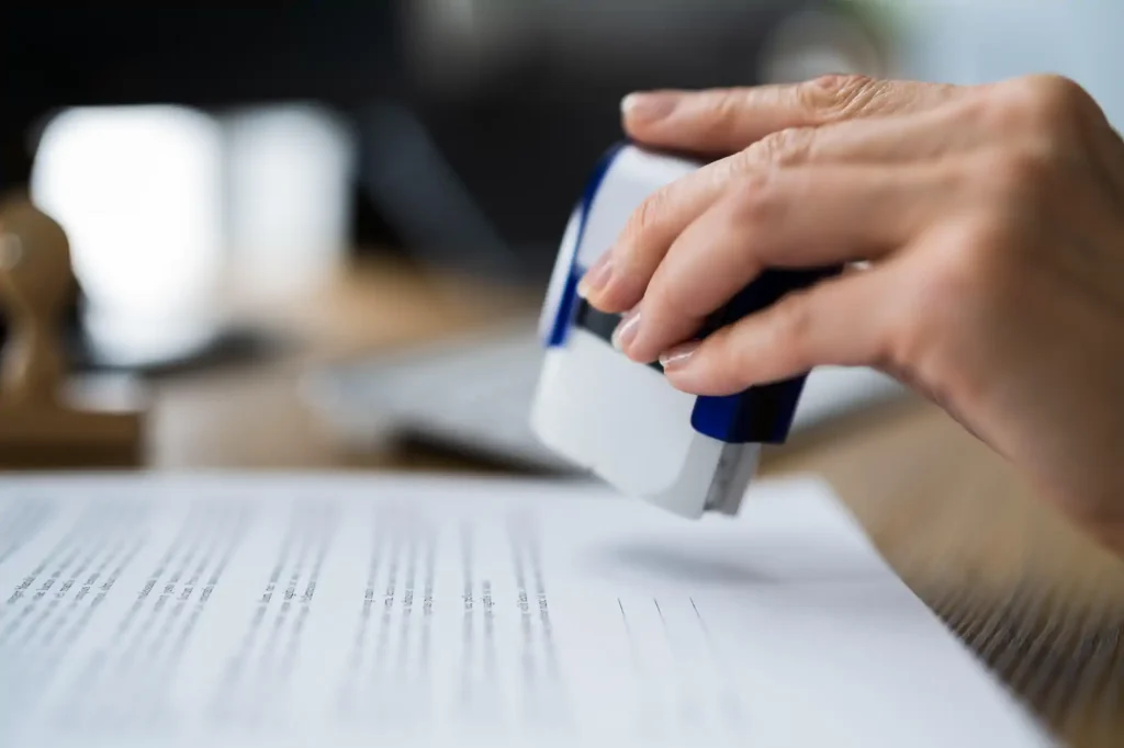 Mano sellando documento oficial en escritorio