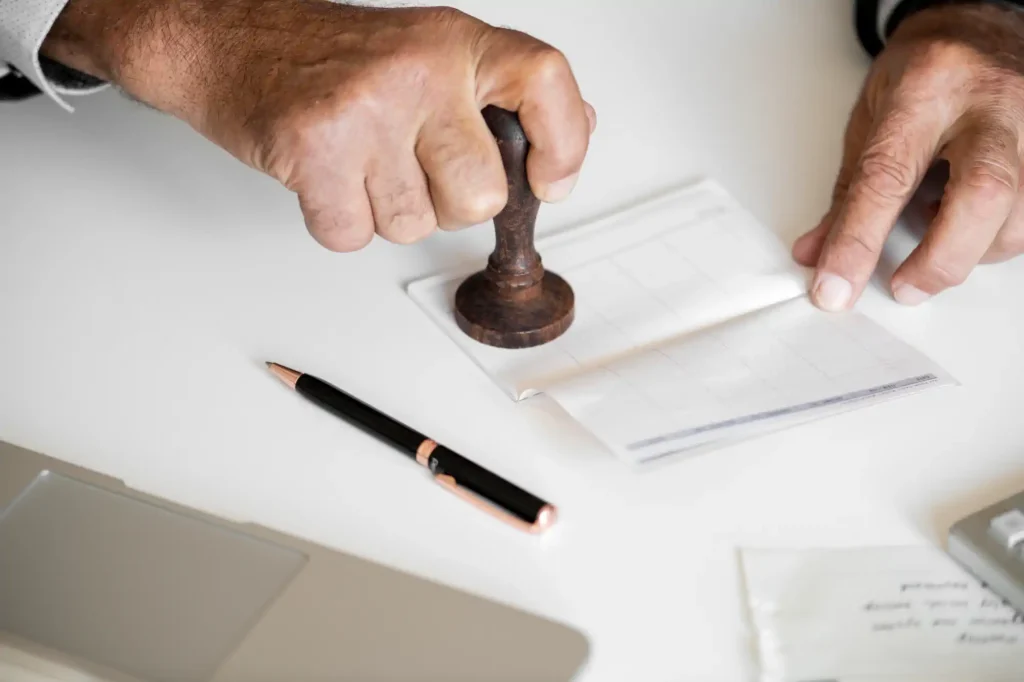 Mano sellando documento oficial sobre escritorio