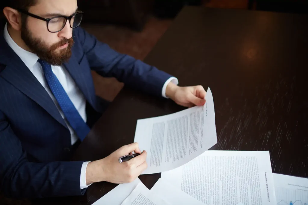 Hombre revisando documentos en escritorio con pluma