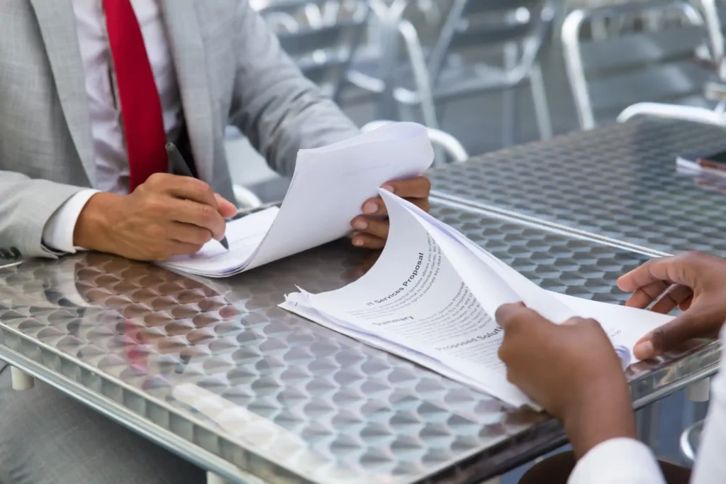 Personas firmando contrato en mesa metálica