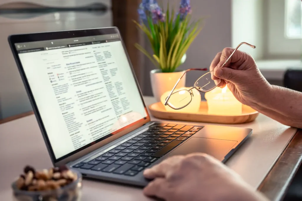 Persona sostiene lentes frente a laptop con documentos