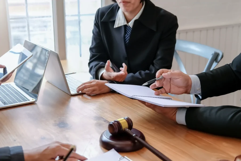 Abogados revisan documentos junto a laptops y un mazo judicial