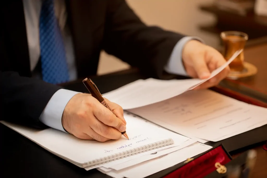 Hombre de traje firma documentos junto a un mazo judicial