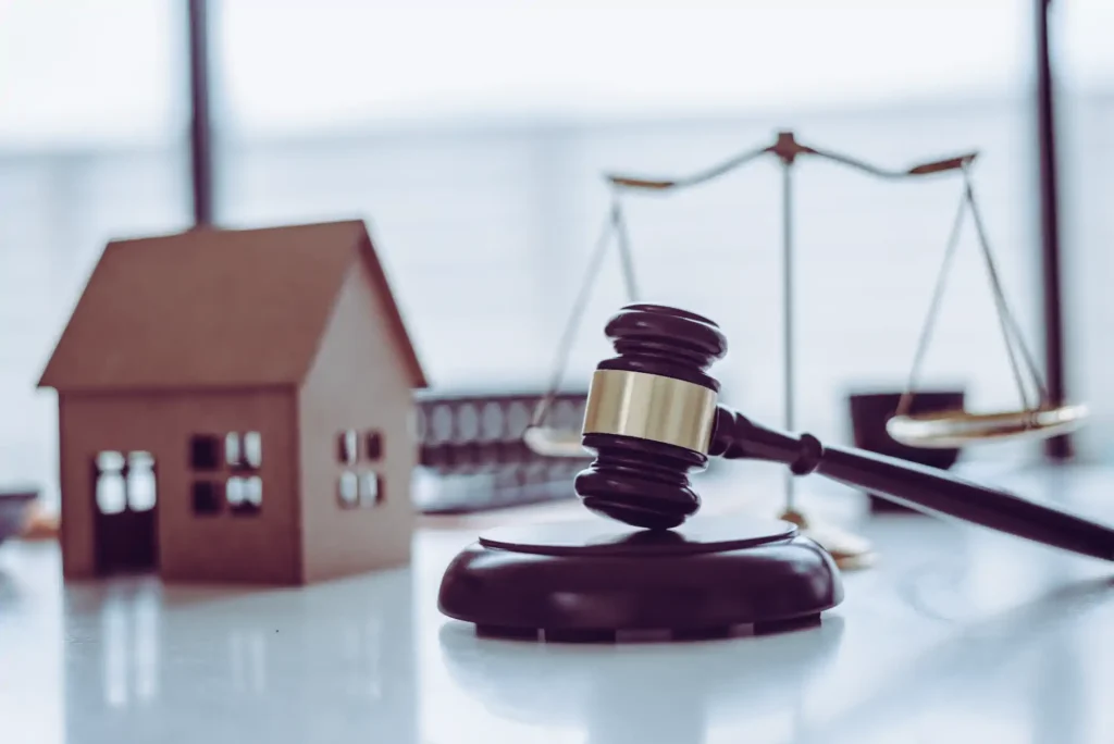 Mazo judicial, balanza y maqueta de casa