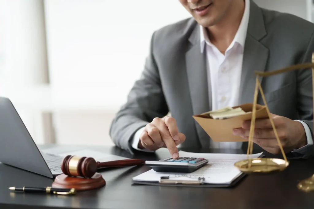 Abogado calcula honorarios junto a balanza y mazo judicial