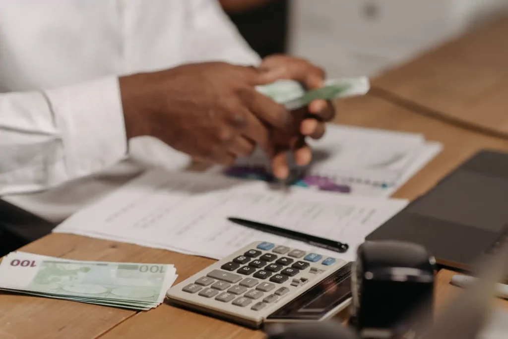 Persona contando billetes junto a calculadora y documentos